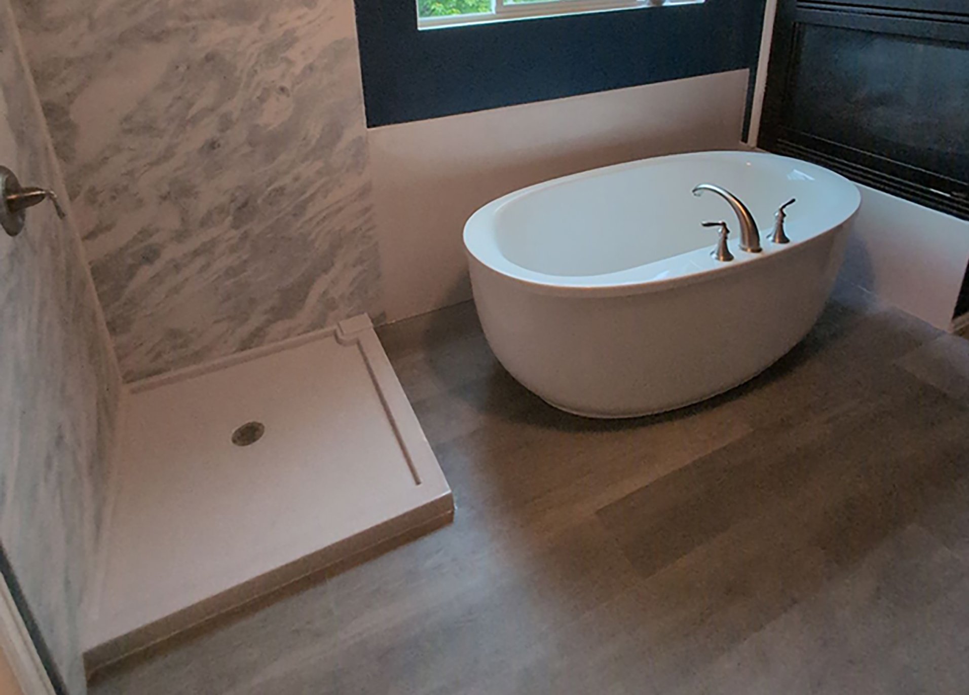 Modern bathroom remodel in Denver featuring freestanding soaking tub and walk-in shower base with marble wall surround