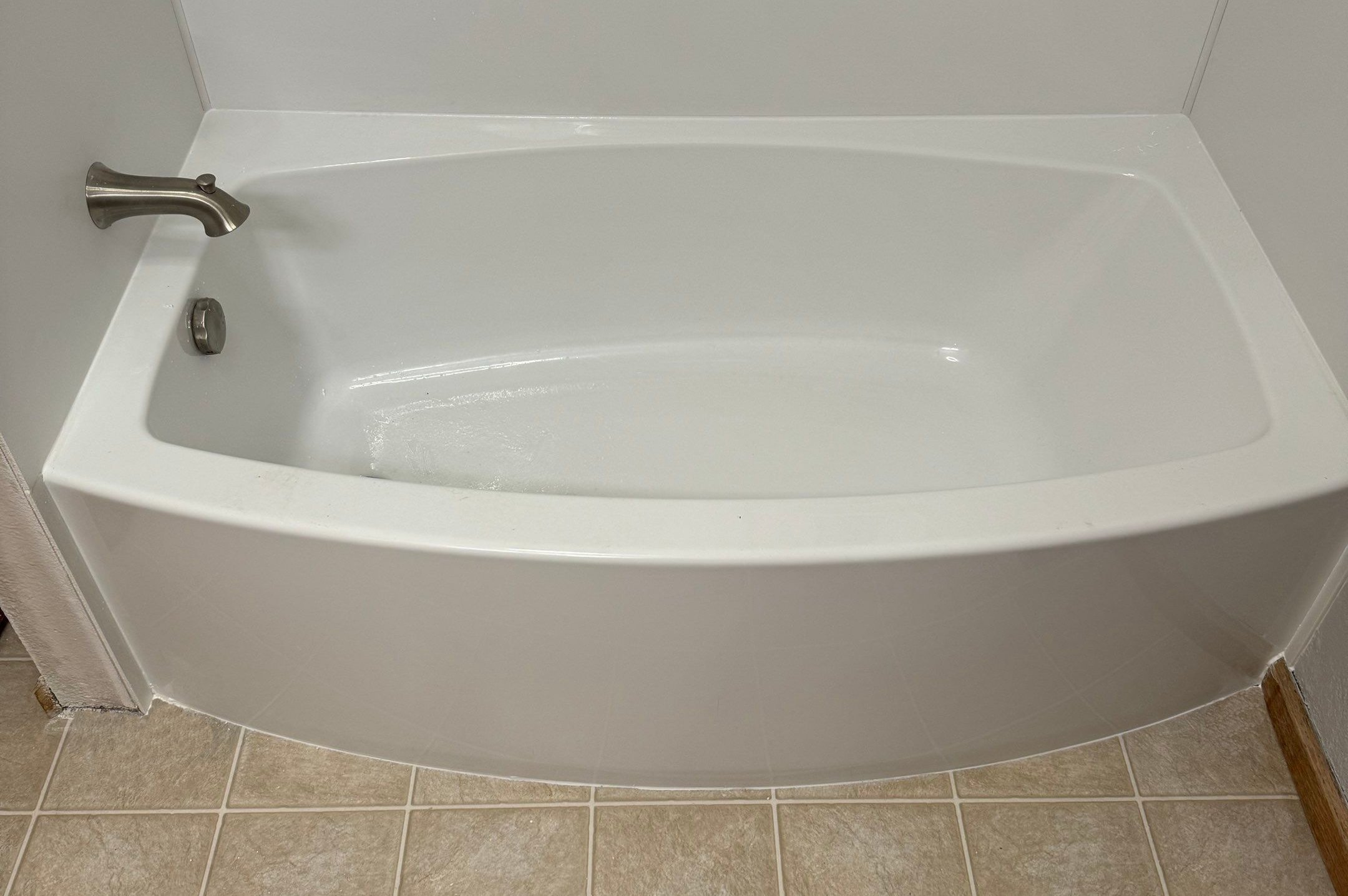 White bathtub replacement in Holyoke, CO home with brushed nickel faucet and tiled flooring.