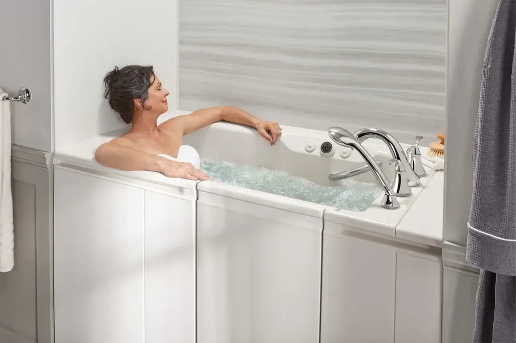 Senior woman relaxing in a white walk-in bathtub with bubbling water jets and chrome fixtures in a modern bathroom.