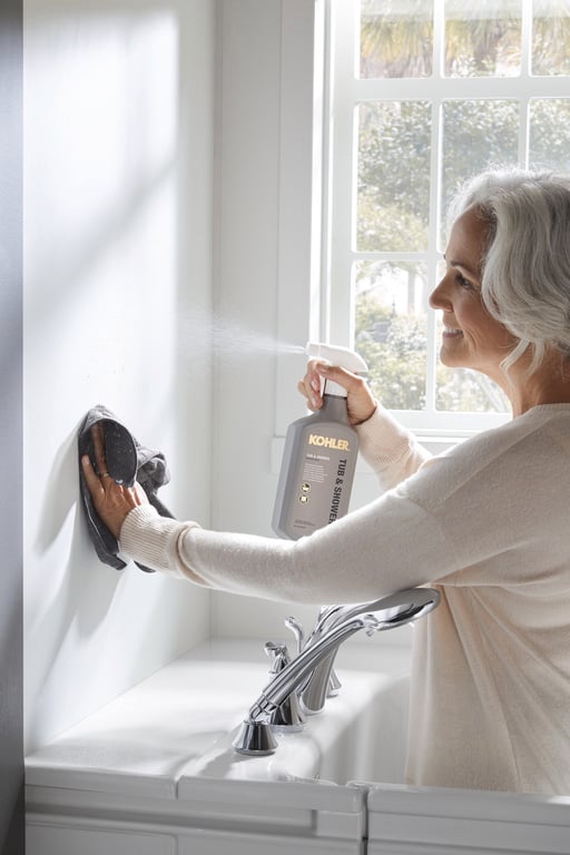 Woman cleaning bathroom wall with KOHLER tile and surface cleaner in Denver, Colorado